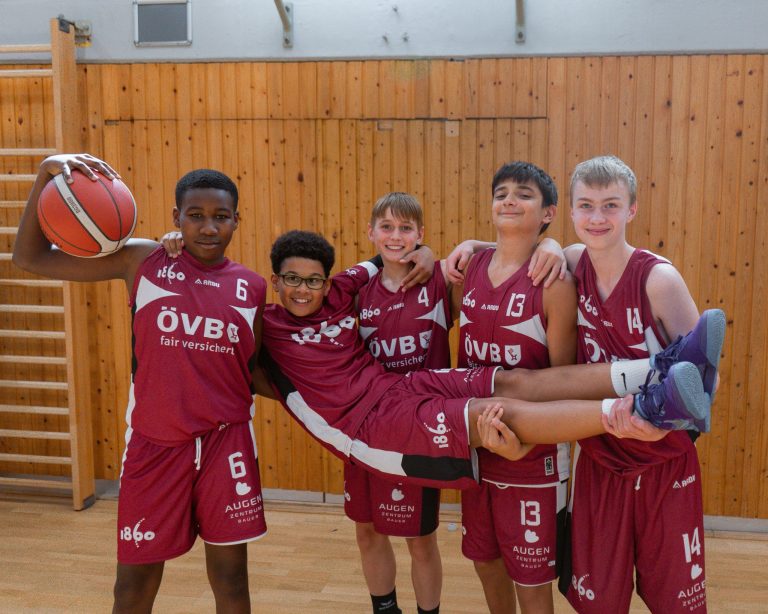 Fünf Jugendspieler albern mit einem Teamkollegen auf den Armen